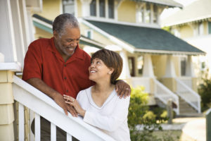 Happy older couple in front of house